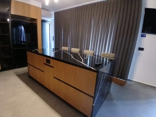 Reception desk in a modern office with high stools and a wooden, black finish.
